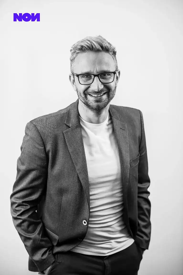 International SEO Specialist Rafał Moszkowcow Chomsky giving a thumbs up, seated on a red British telephone box