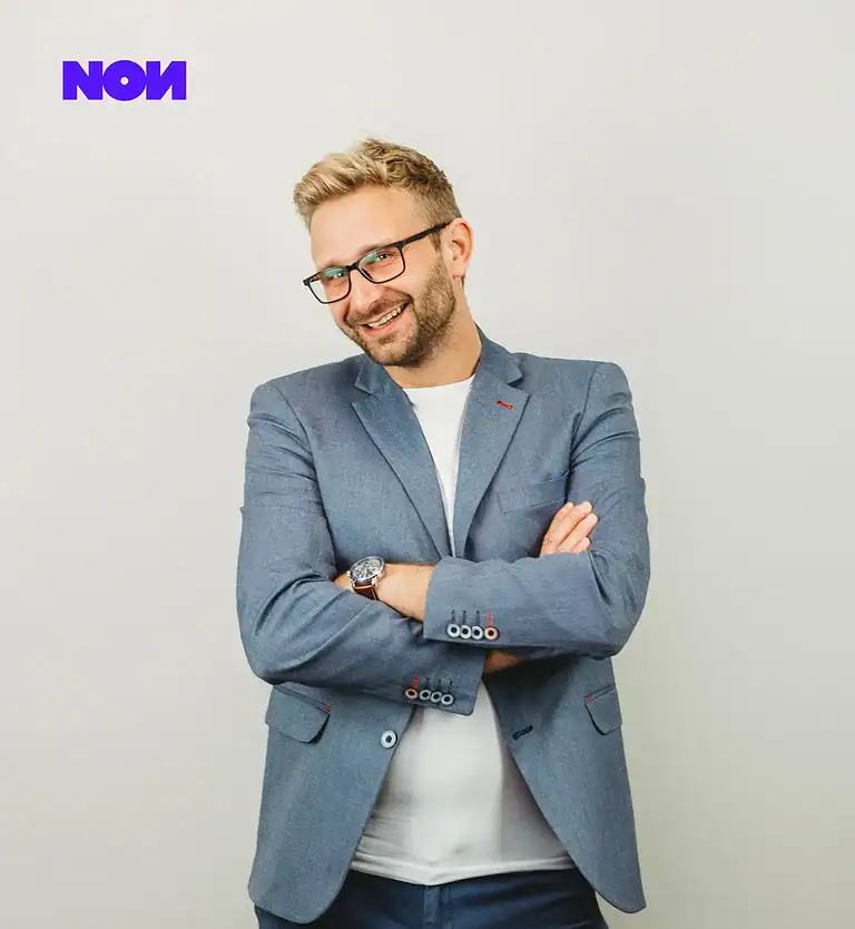 Rafał Moszkowcow Chomsky, International SEO Specialist at non.agency, relaxed seated pose in a pink shirt