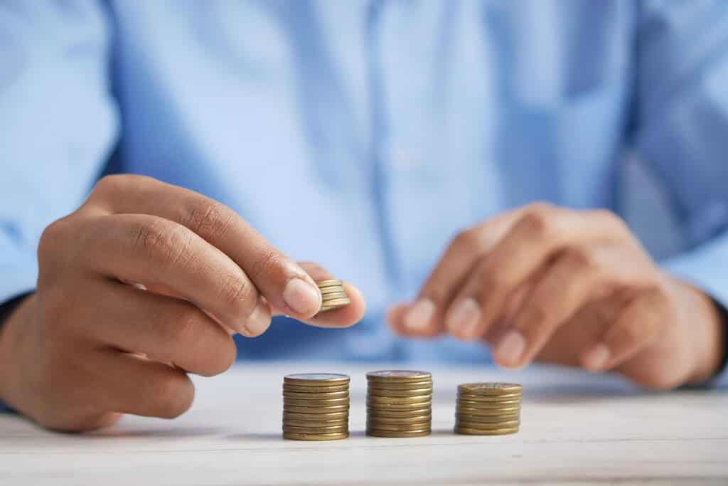 Person arranging stacks of coins on a table.
